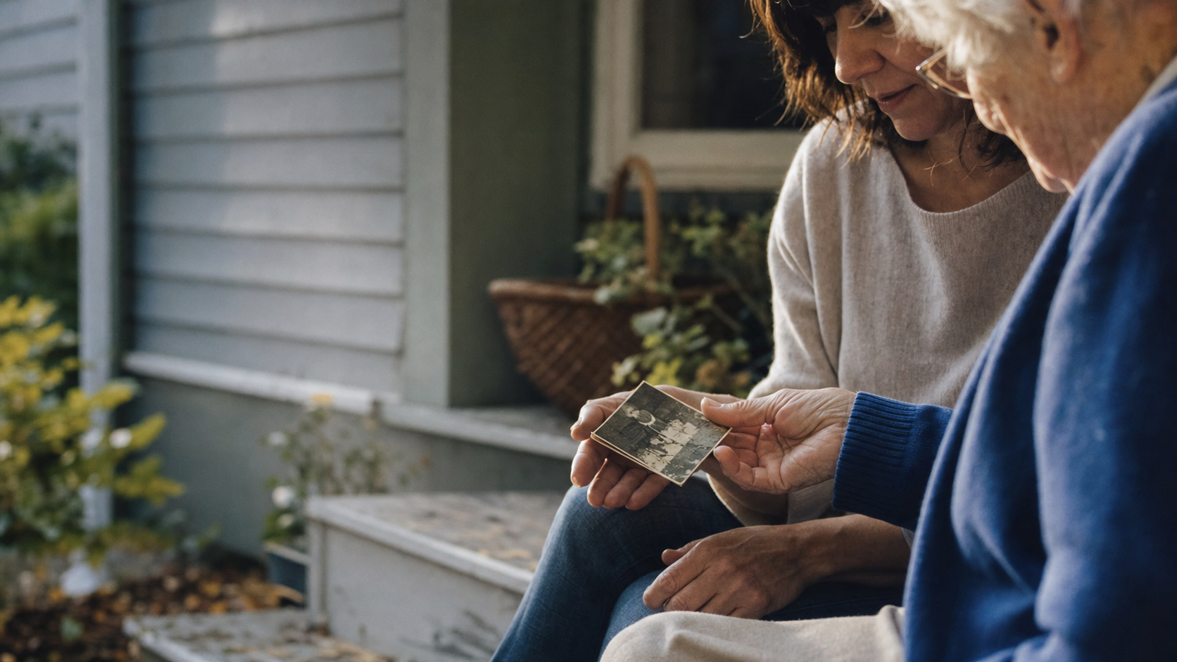 An adult and an elderly parent look at a worn family photograph together.